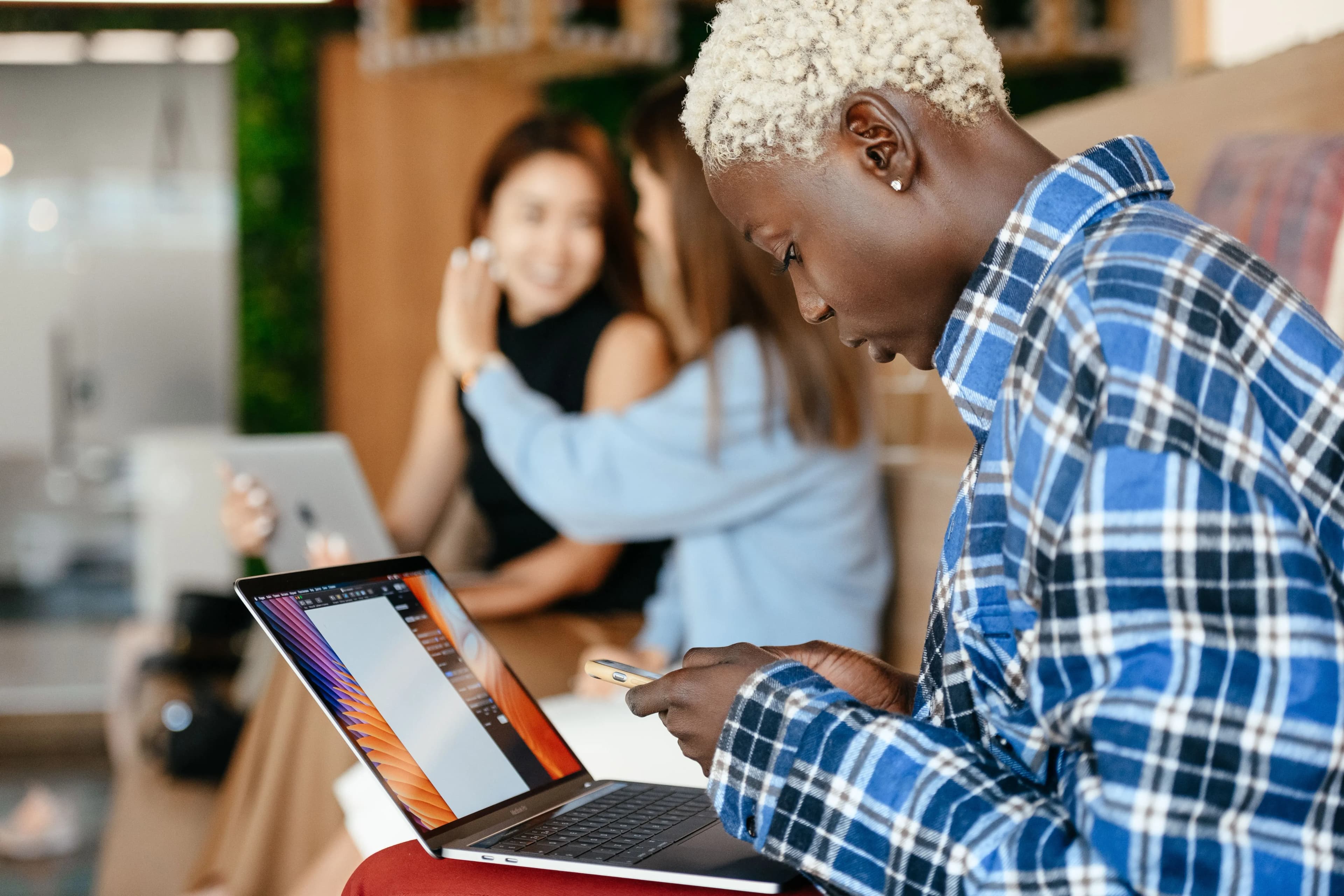 Someone working through notes on a laptop while colleagues talk behind them