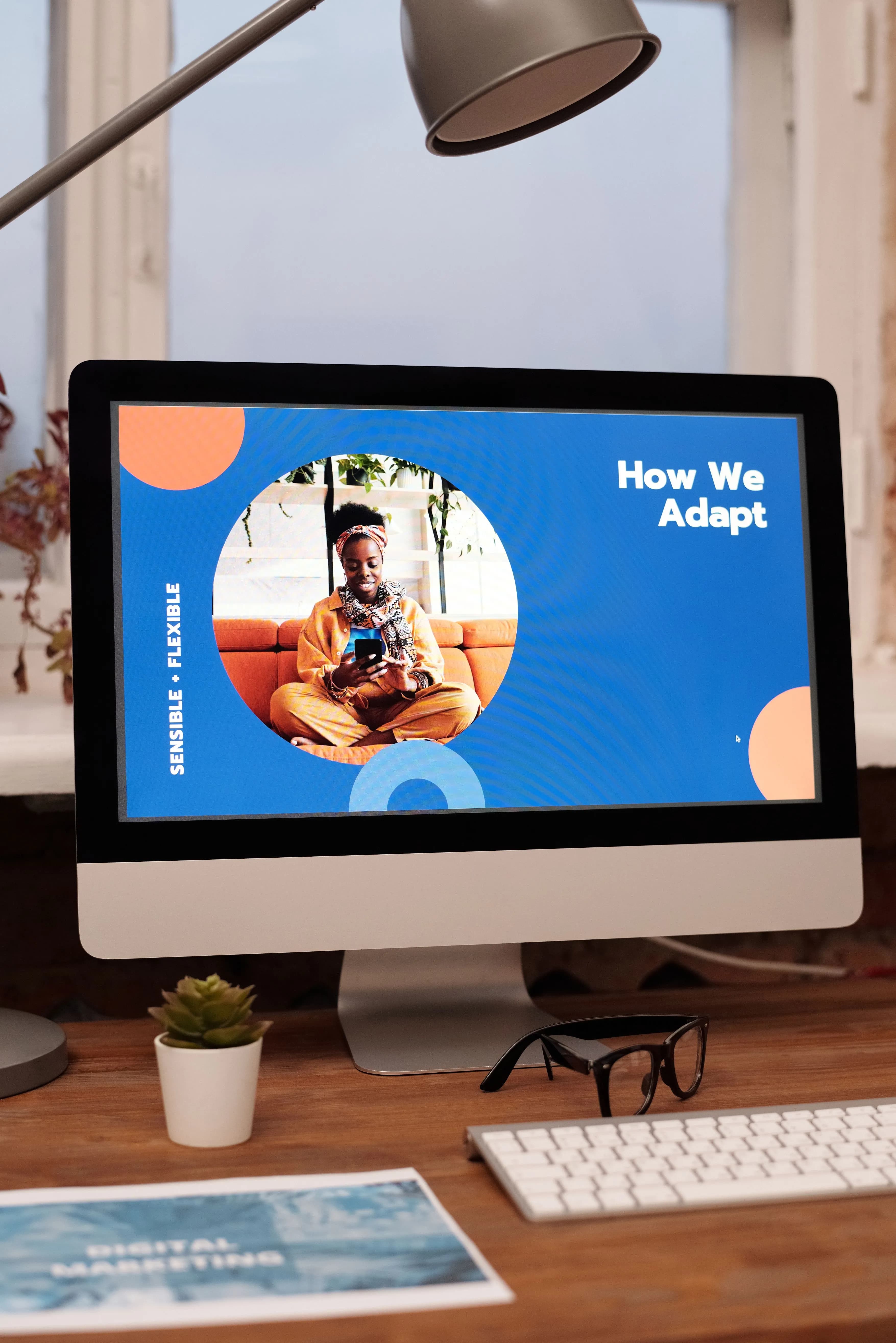 An iMac on a studio desk showing a slide from a brand presentation