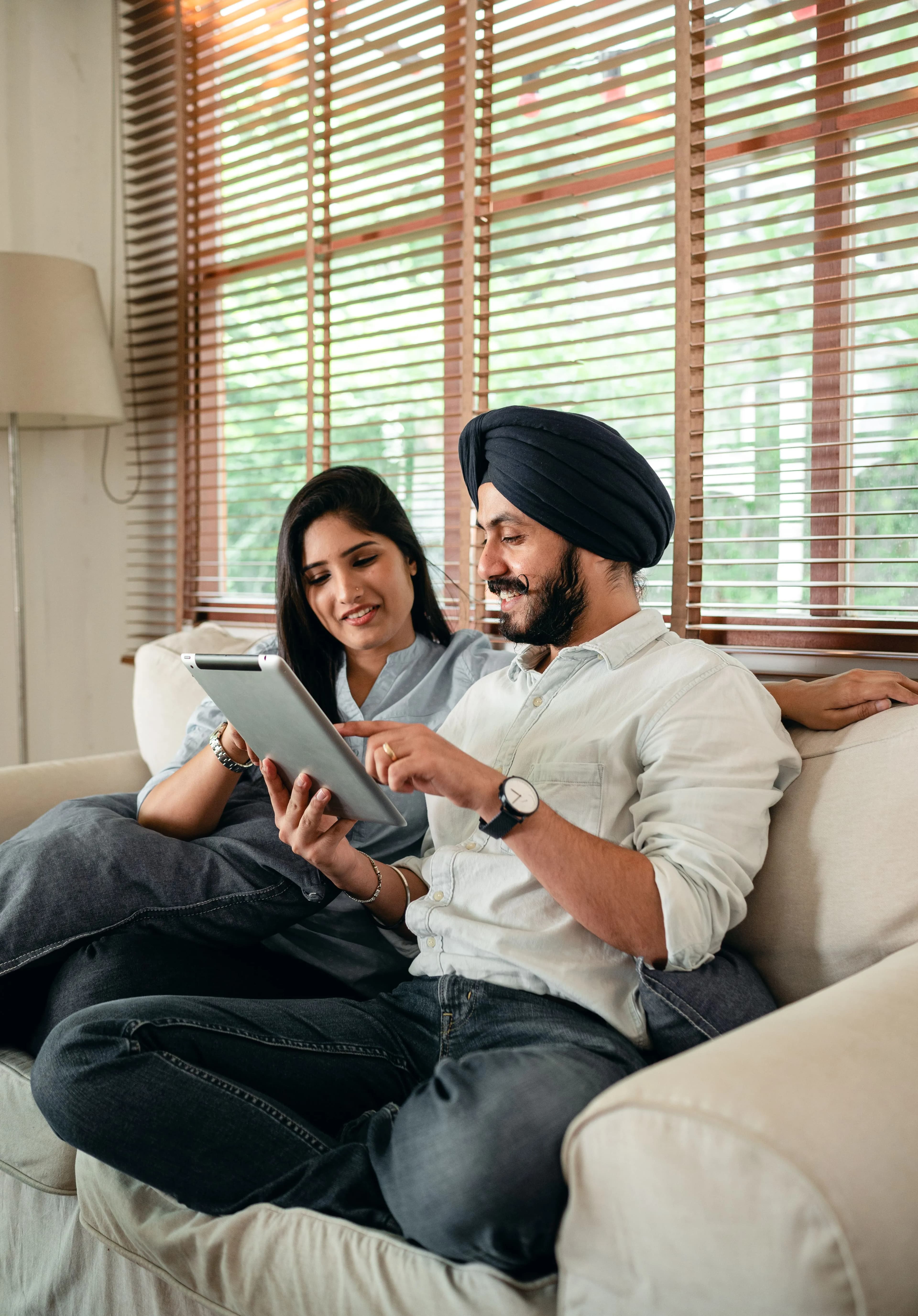 Two people on a sofa looking together at a tablet in warm daylight